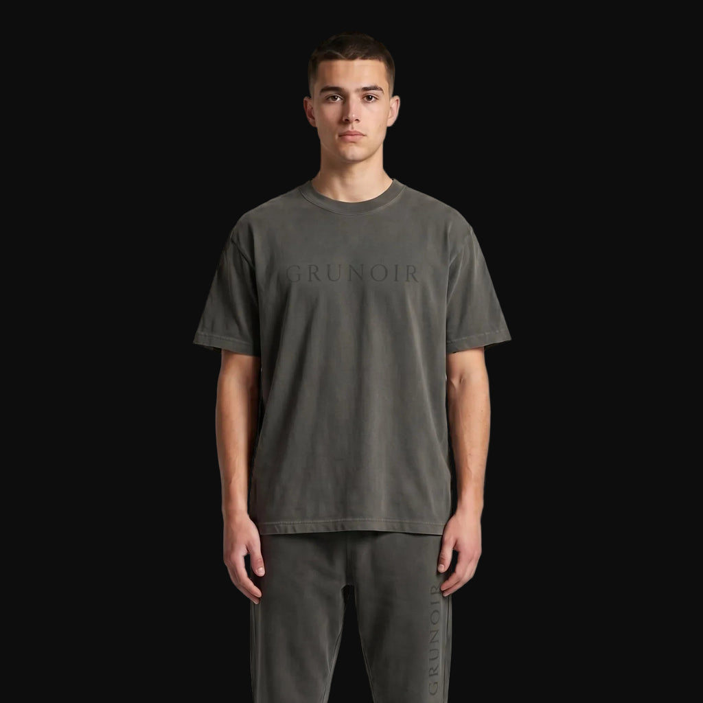 Man wearing a dark gray t-shirt and matching jogger pants on a light gray background