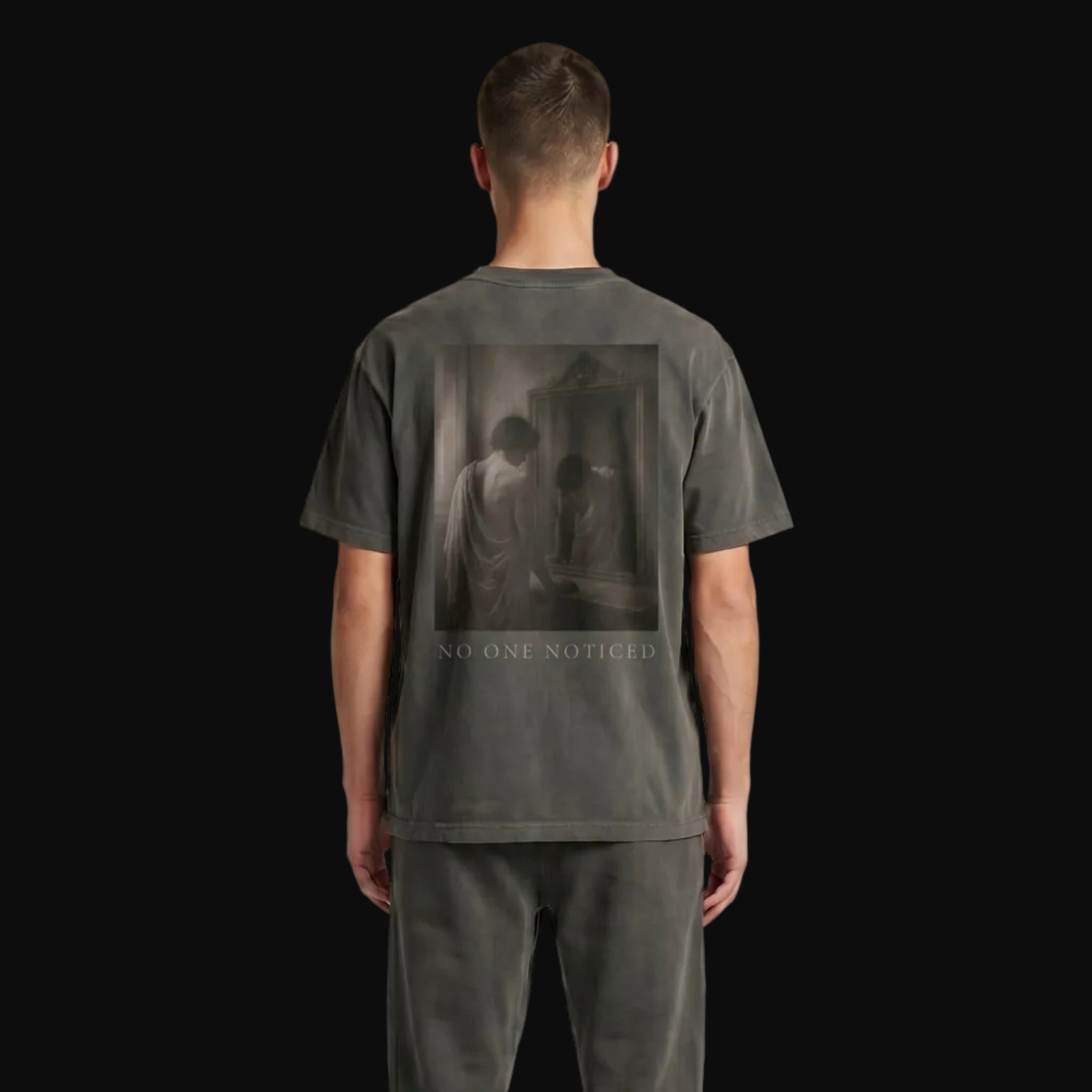 Person wearing a dark gray t-shirt and pants on a plain background